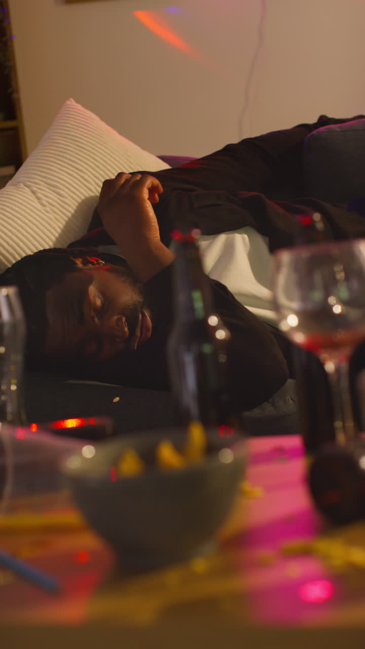 video vertical de un hombre borracho tendido en el sofá en una fiesta en casa