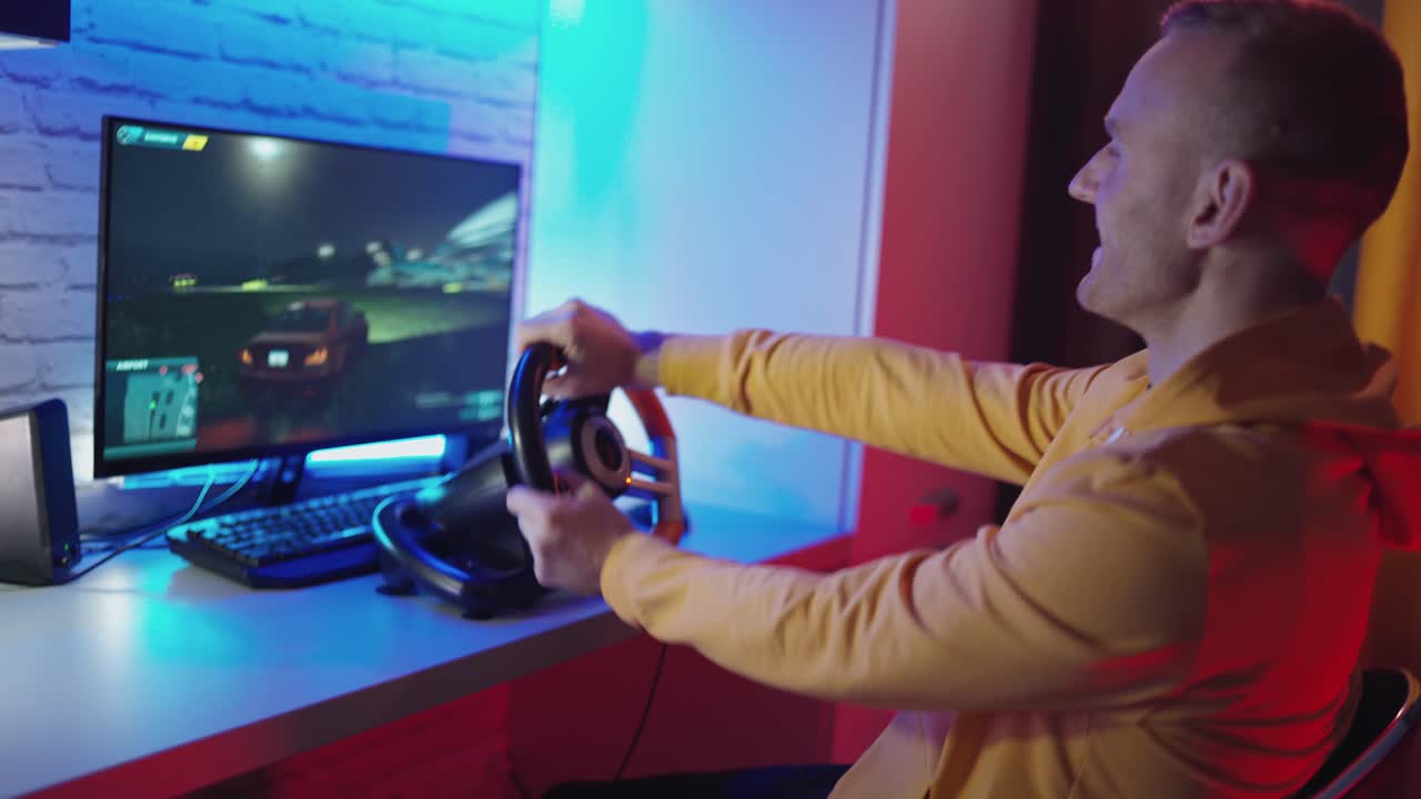 Giovane giocatore seduto a casa. Giovane uomo con computer che gioca a un videogioco di corse automobilistiche a casa.