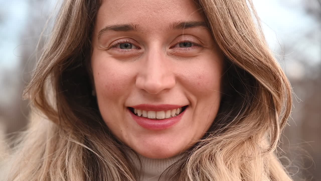 Close up of a blonde woman smiling in a park in daylight
