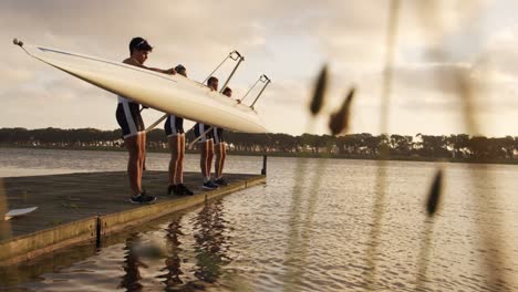 equipo de remadores masculinos sacando del lago el bote