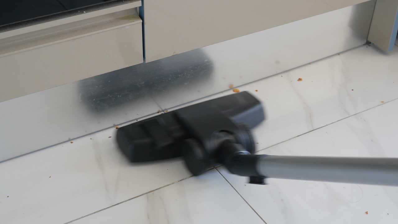 cerca de un aspirador limpiando un piso de azulejos en una cocina