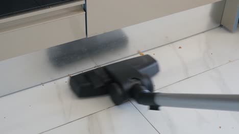 close up of a vacuum cleaner cleaning a tiled floor in a kitchen