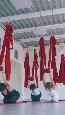 slim ladies and handsome man relax after hard workout with fly yoga hammocks and stretch legs low angle shot