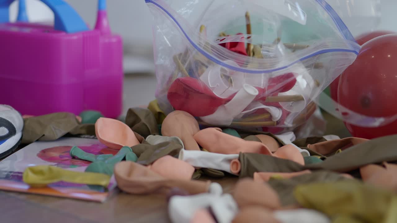 globos vacíos con máquina de bomba de aire a su lado esperando ser llenados tendidos en el suelo de madera dura mientras la familia se prepara para la celebración de la fiesta del evento de la boda - en el cine 4k