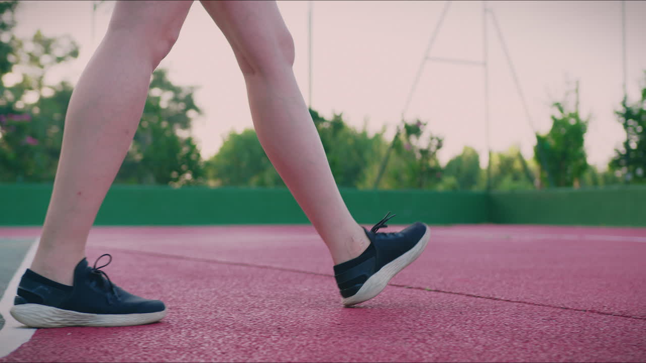 농구 경기장 소녀는 느린 동작으로 공을 드리블하며 낮은 각도로  ⁇ 니다.