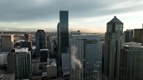 lowering aerial of seattle skyscrapers reflecting elliot bay and steam billows on windows