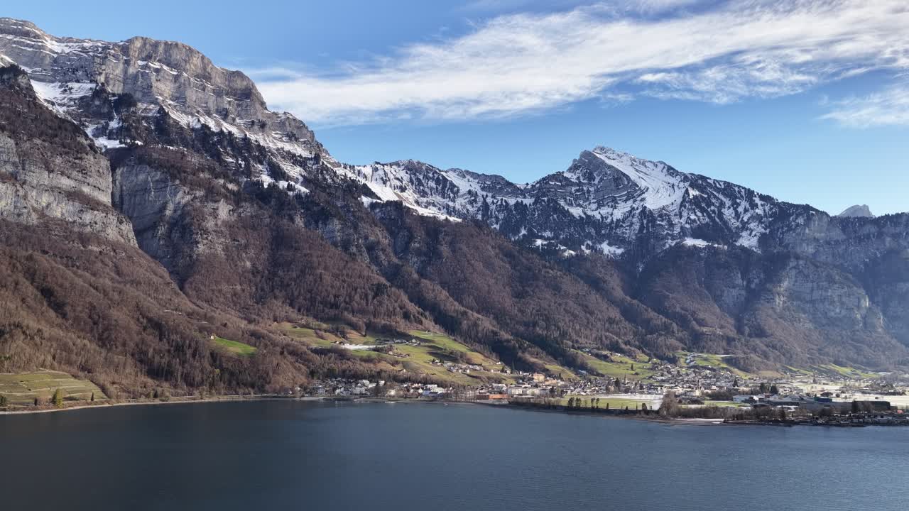 Dãy núi Churfirsten ở Thụy Sĩ, nhìn ra hồ Walensee gần Walenstadt, với góc nhìn từ drone bao quát các đỉnh núi An-pơ, ngôi làng ven hồ, bầu trời mùa đông quang đãng và khung cảnh châu Âu thanh bình.
