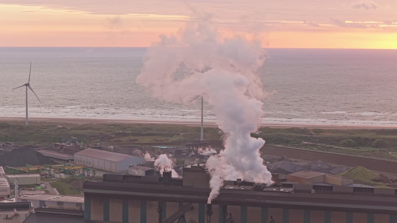 Drone capture of industrial chimneys smoking at golden hour landscape