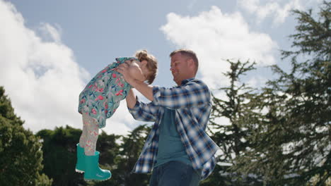 happy father and daughter playing together in backyard garden happy little girl having fun with dad holding child playfully swinging his kid enjoying childhood freedom outdoors 4k