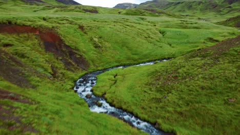 scenery of rocky river with tourist walking along the bank in the valley of reykjadalur, iceland