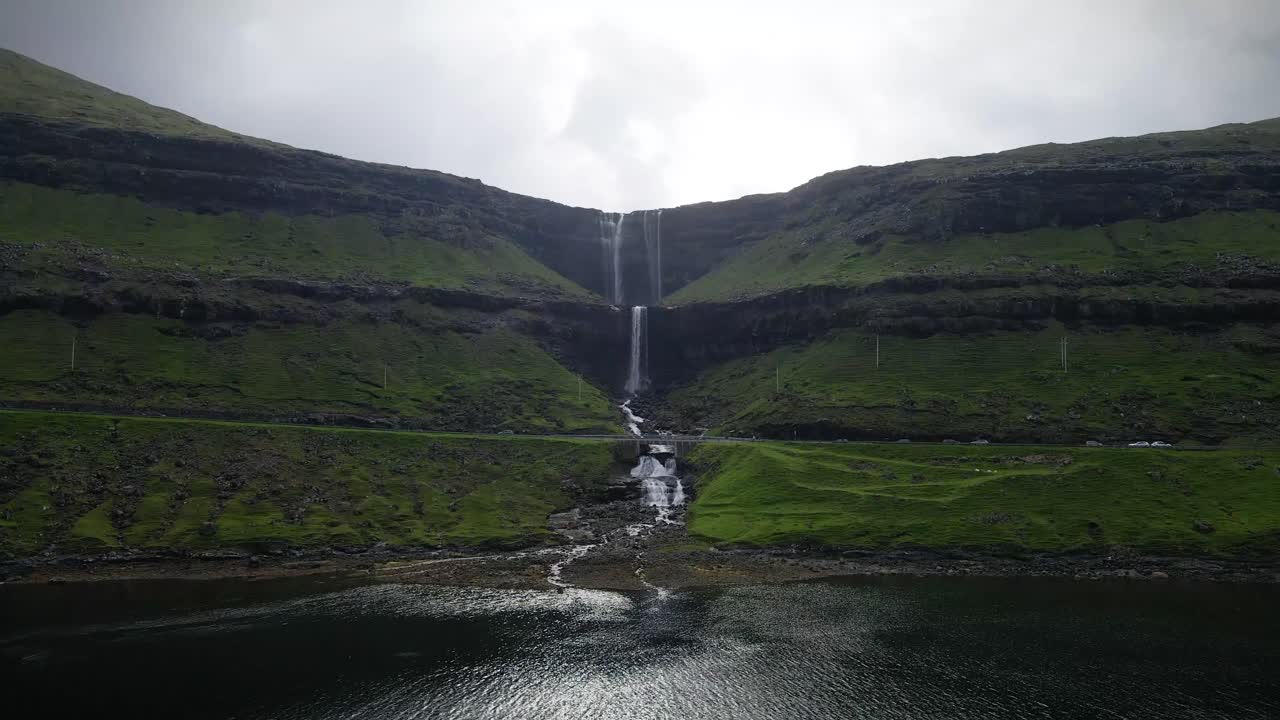 la cascada de fossa, la más alta de las islas feroe, cae elegantemente a través de escarpados acantilados y exuberante vegetación, creando una escena tranquila y cautivadora a medida que desemboca en una serena cuenca de agua.
