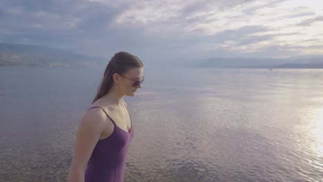 Side-close-view-of-attractive-young-girl-walking-by-mountain-lake