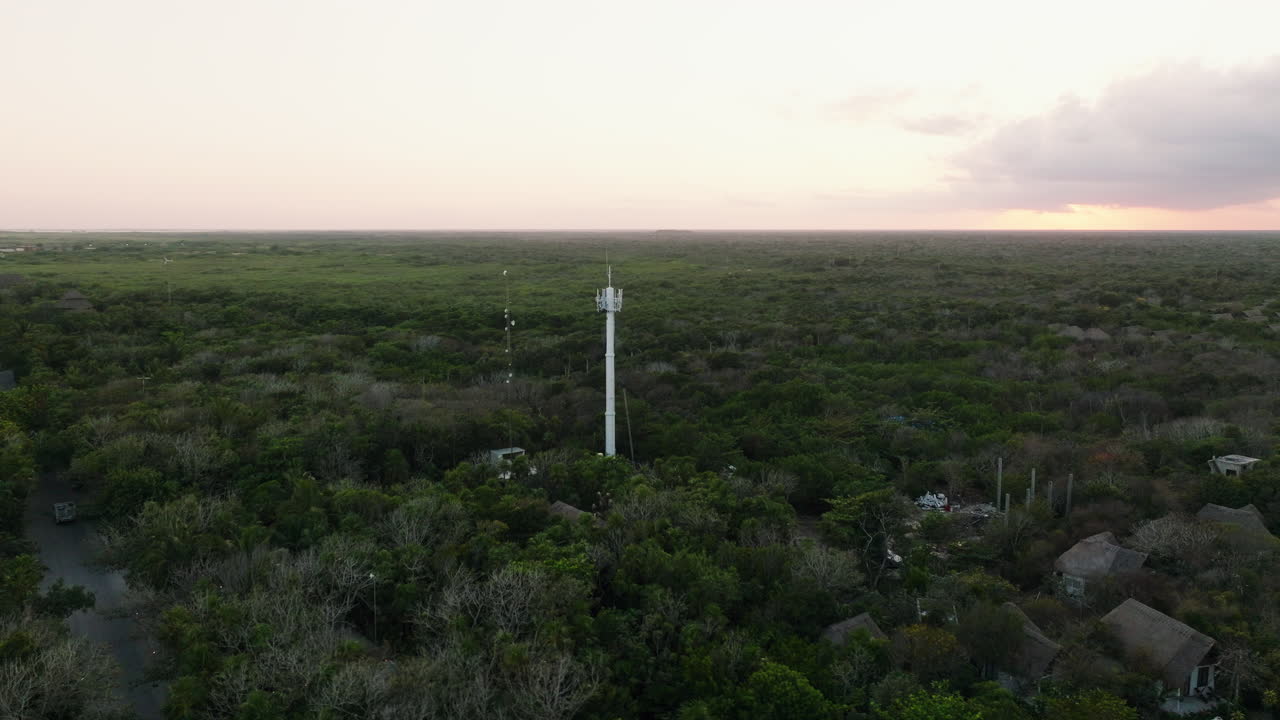 vista aérea del complejo costero y la selva con la torre de comunicación al atardecer