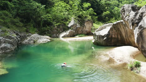 aerial shot of a man swimming peacefully in a calm, magical nizao river