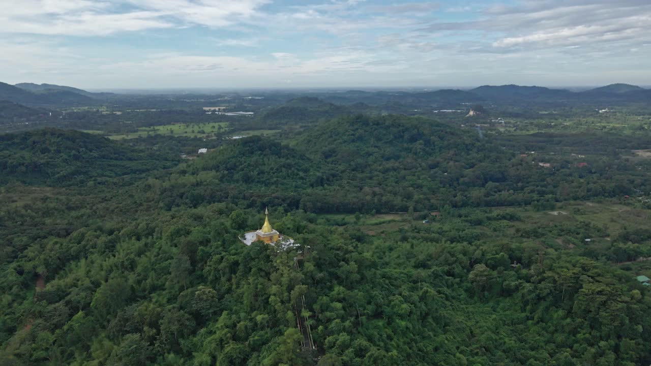 Stupa doré Phra Maha Chedi Thep Nithakorn au-dessus d'une colline boisée dans la province de Saraburi, Thaïlande