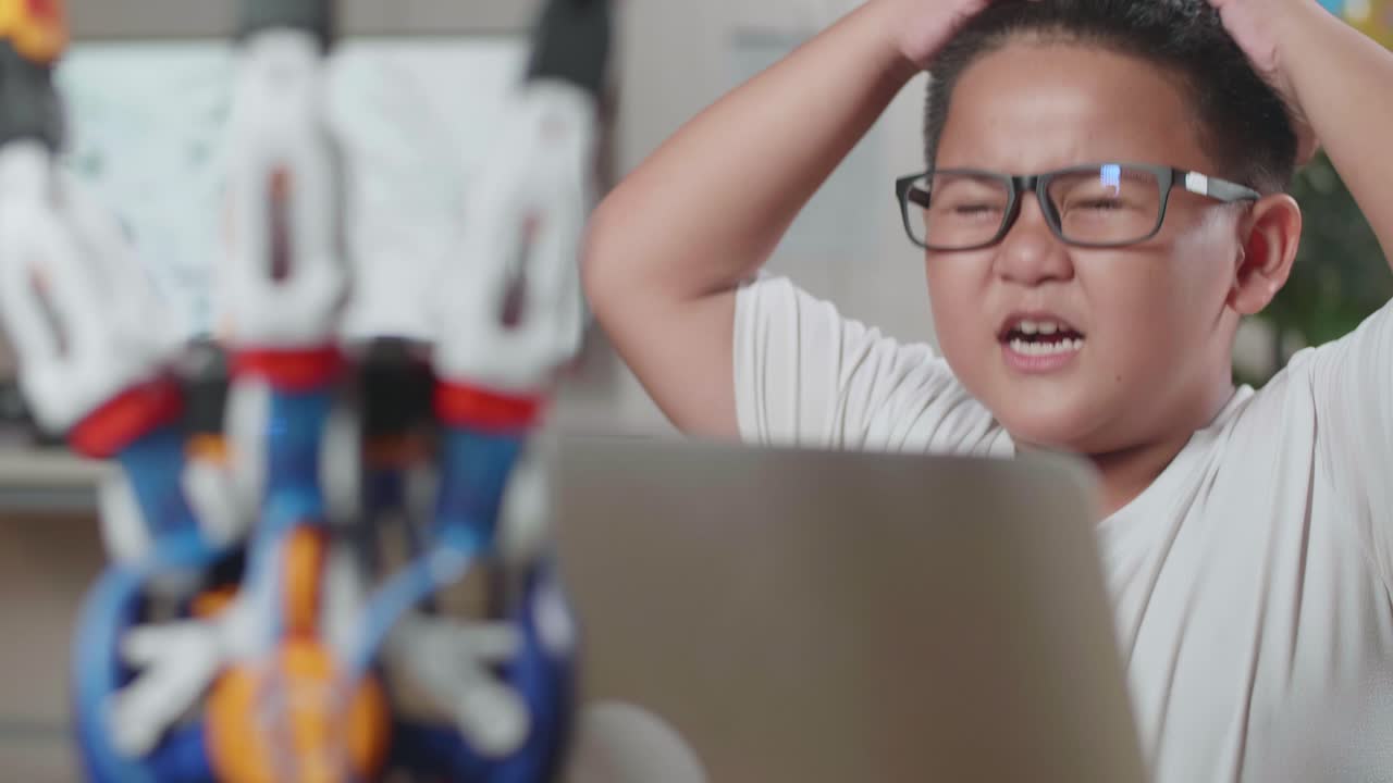 집에서 노트북을 사용하는 사이보그 손에 대해 작업하는 동안 두통을 고 있는 아시안 귀여운 소년의 클로즈업