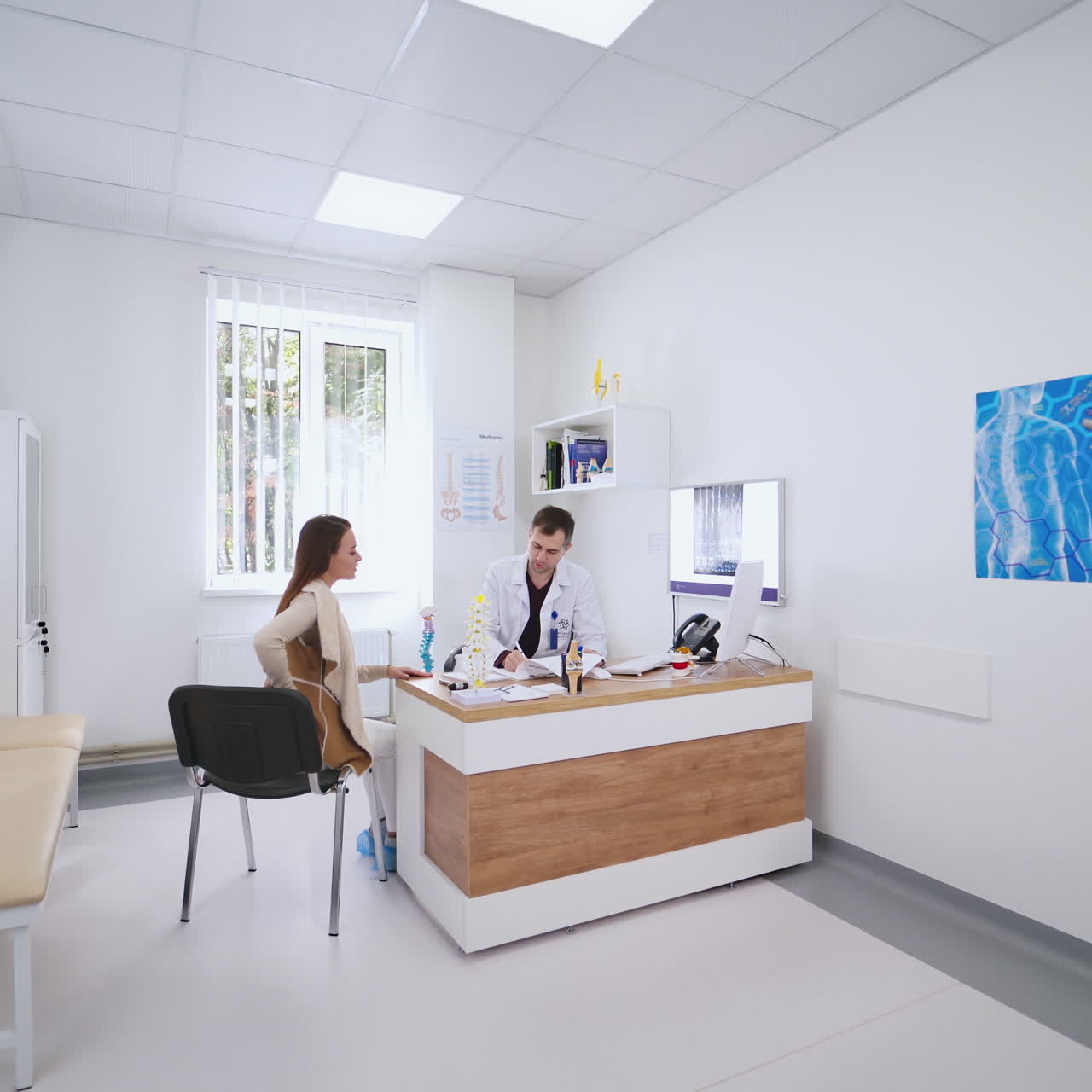 Young woman having a chat with a doctor. Male doctor talking to a female on the modern office background in clinic. Medical care concept.