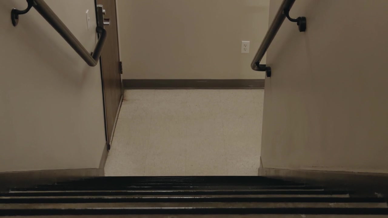 Upward rising glide reveals an indoor stairwell landing with handrails