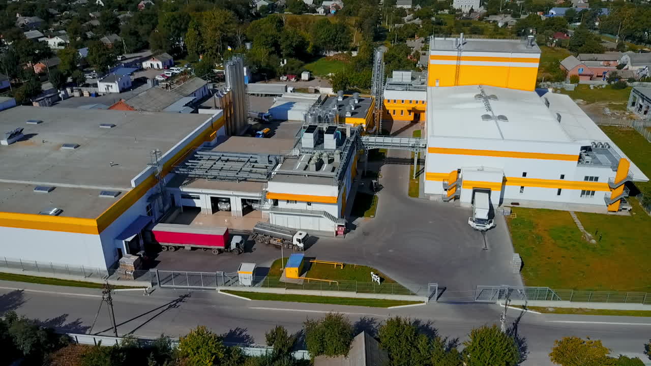 Flight over the well-kept territory of a white and yellow building of a plant. Circle movement over the industrial zone and neighboring area.