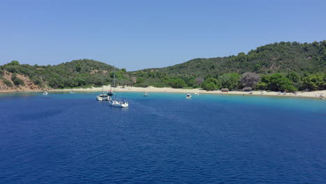 Aéreo:-Volando-Entre-Veleros-Y-Catamaranes-En-La-Playa-De-La-Isla-Tsougria-Cerca-De-Skiathos,-Esporadas,-Grecia