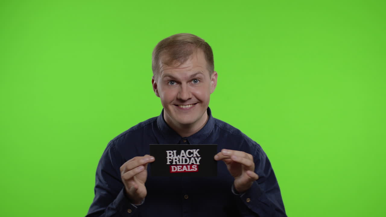 행복한 남자가 미소 짓고, 춤을 추고, 블랙 프라이데이 거래를 보여주고, 기하고, 좋은 할인을 즐기고 있습니다.