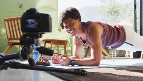 Happy-fit-african-american-man-exercising-at-home,-doing-press-ups-and-filming-fitness-vlog
