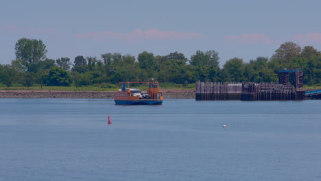 orange roll-on, roll-off ferry leaving the prison dock at hart island, with white prison bus