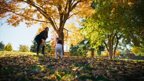 family playing in autumn leaves