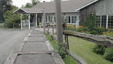 caminando por una escalera de grava junto a una antigua valla de madera hacia una hermosa mansión de madera gris en el centro de eventos y bodas de strathmere