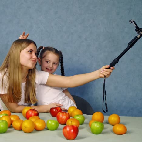 . mother making selfie with daughter. young mother with daughter making selfie at table with fruits