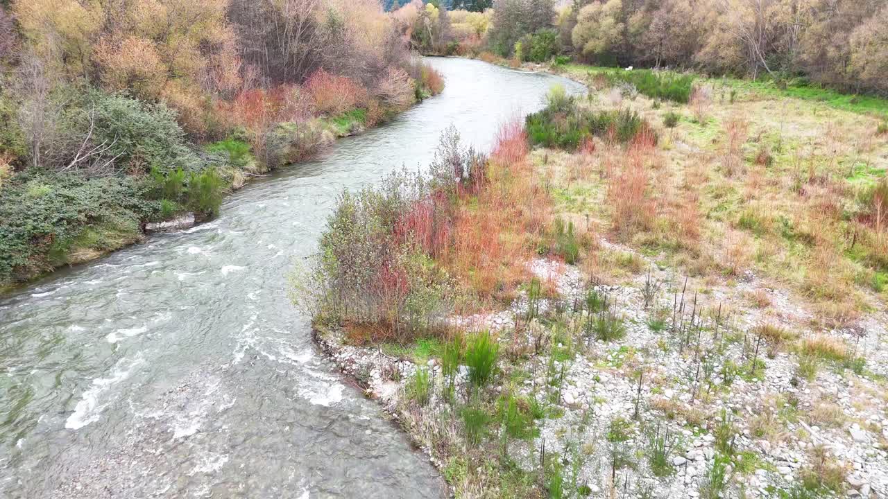 A tranquil river winds through lush vegetation at Lake Tekapo, captured in soft, natural lighting with gentle camera movement