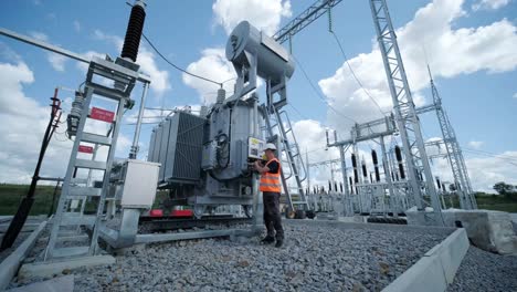 electrical engineers inspect the electrical systems at the equipment control cabinetю high voltage transformer against the blue sky. electric current redistribution substation