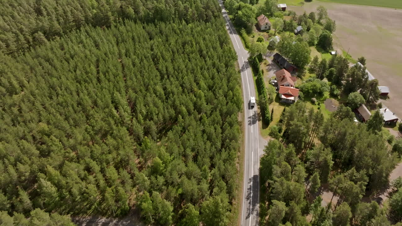 Aerial view following a motorhome driving in middle of forest and rural nature
