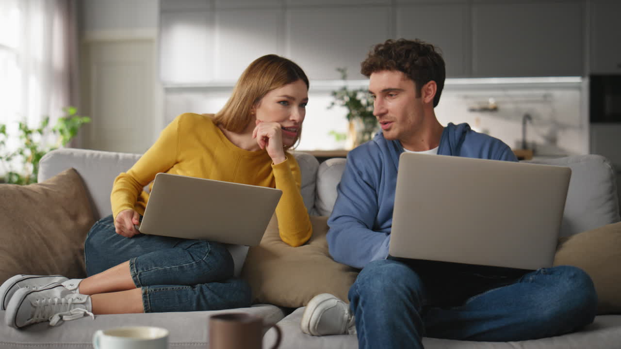 Excited woman looking man computer asking at home closeup. Couple lifestyle