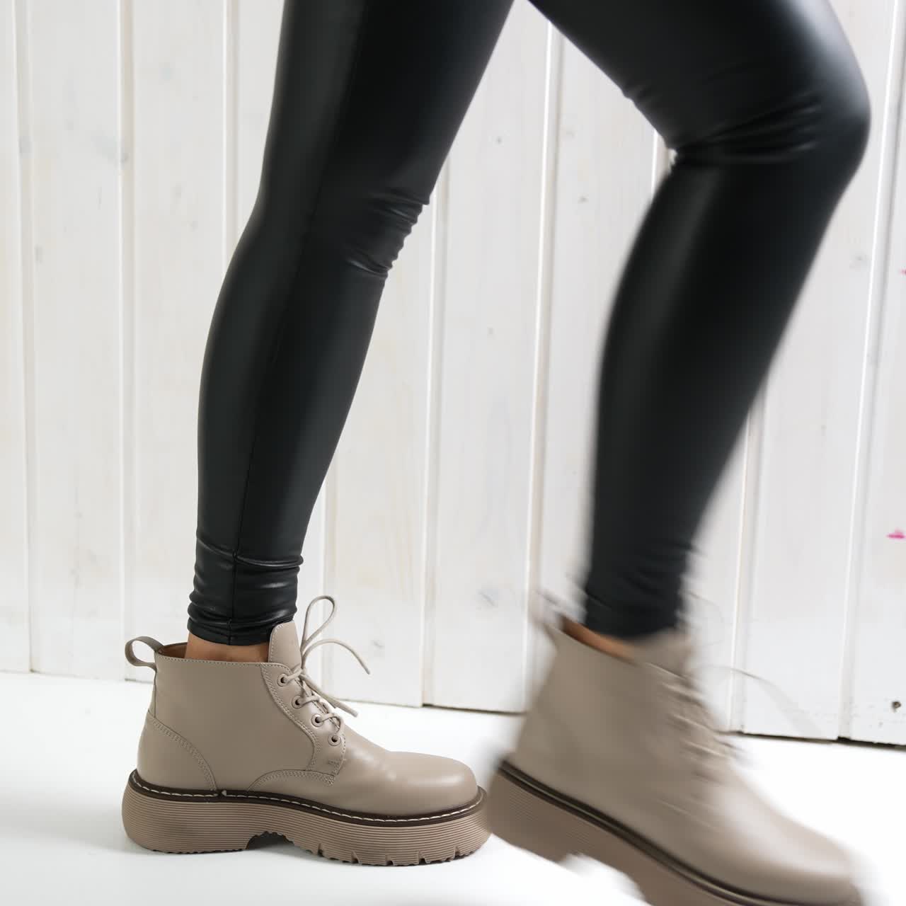 Comfortable leather beige boots on a girl in black leggings. Lady dances to show the beautiful and modern footwear