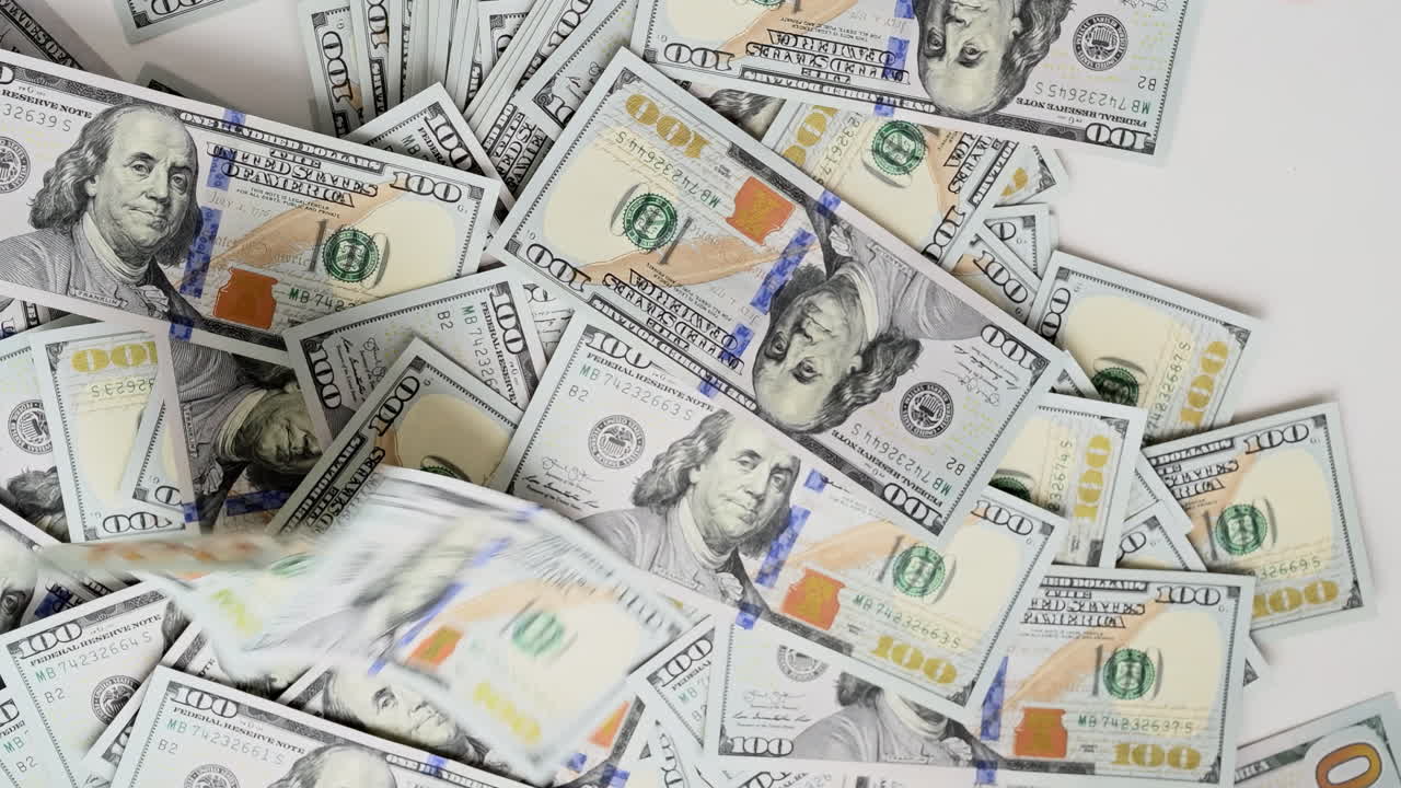 A man's hands quickly count a stack of one hundred dollar bills against a light background