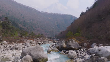 drone captures dudh koshi river flowing through sagarmatha region, boulders on banks, dense forest, and himalayan adventure route for trekkers at mout everest base camp