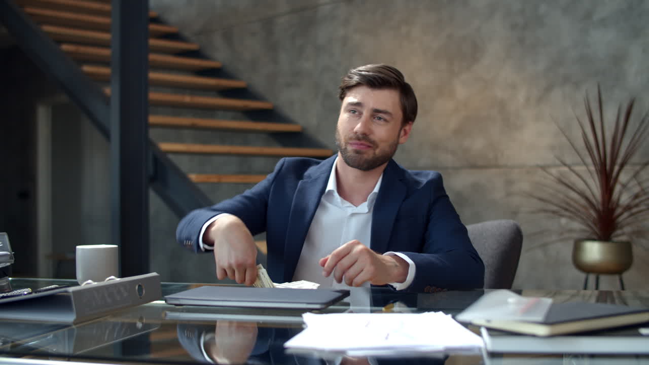 un uomo sorridente che conta i soldi sul posto di lavoro al rallentatore. un ragazzo ha fatto soldi facili.