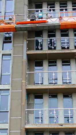 front view of a new modern building. construction of a high-rise apartment. workers doing the outdoor view of a multistorey building. vertical video