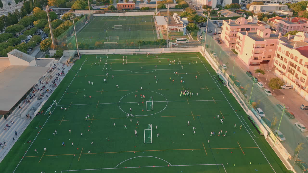 village football stadium at summer evening aerial. Green soccer field