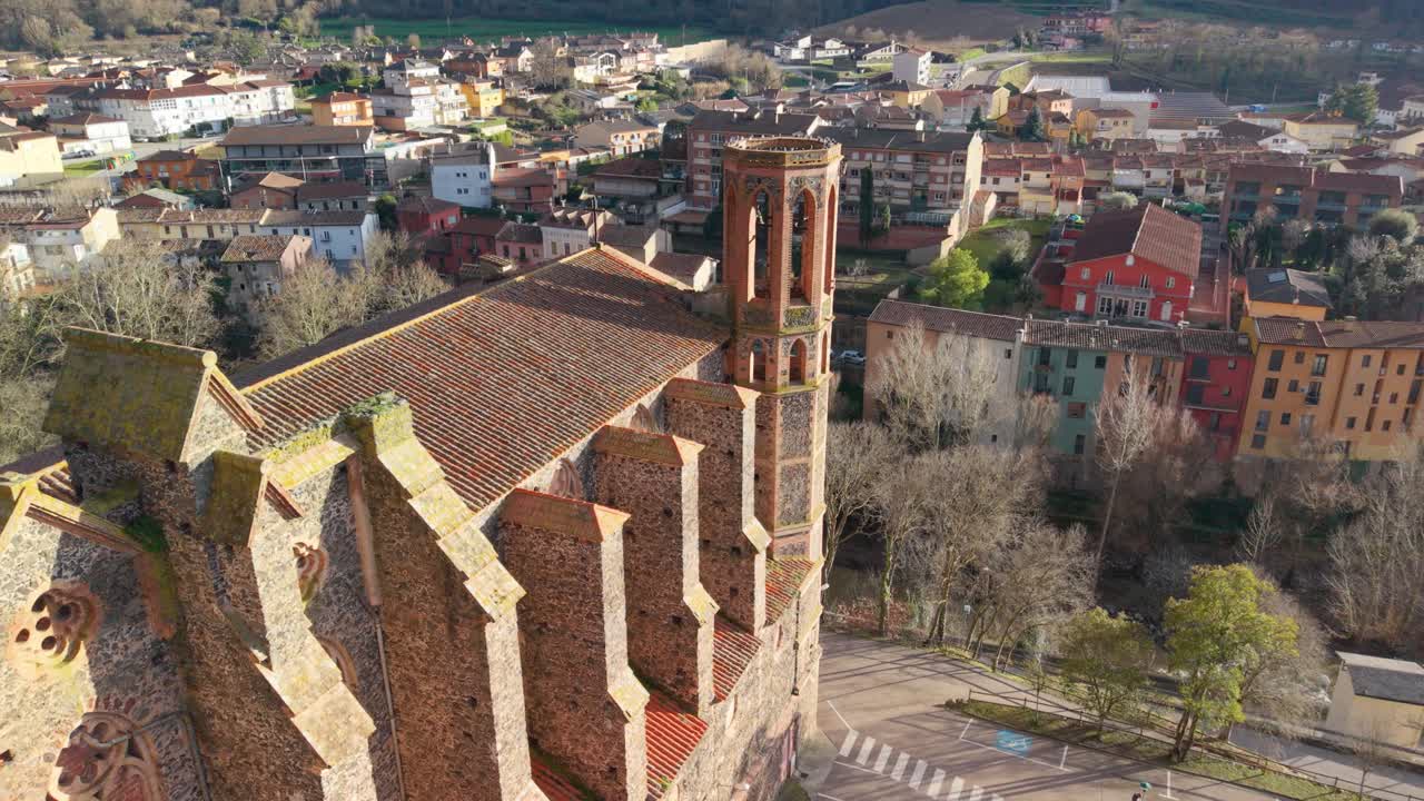 Drone-**optagelser** i kredsløb om det historiske kloster Sant Joan Les Fonts i Girona, Catalonien, der viser dets romanske arkitektur, fremtrædende klokketårn og den omkringliggende spanske landsby.