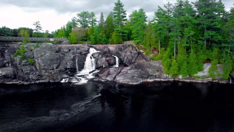 el paisaje rocoso de la cascada sobrevuela en el vibrante norte de muskoka con un lago oscuro, un punto de observación de las cataratas altas con agua que brota