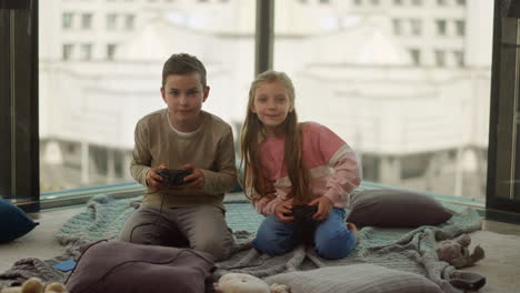 siblings playing computer games. kids holding gamepads in living room.