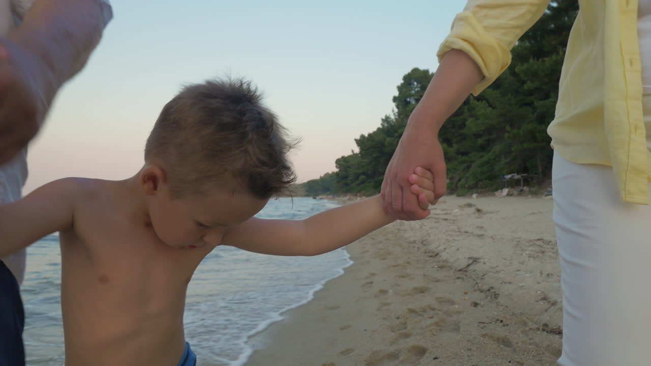 niño con los abuelos caminando por la orilla