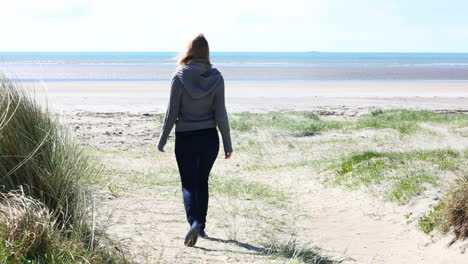 Mujer-Caminando-Por-Una-Playa-En-Un-Clima-Ventoso