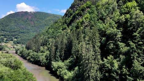 view of aries river and forested apuseni mountain with wooden cross on top in transylvania, romania