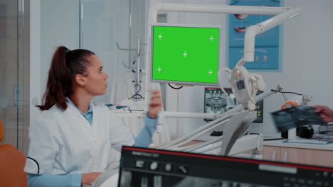 woman analyzing green screen on monitor and teeth x ray