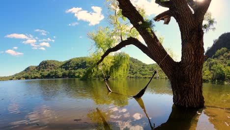 Time-lapse-of-clouds-over-lake-with-hammock-hanging-on-tree