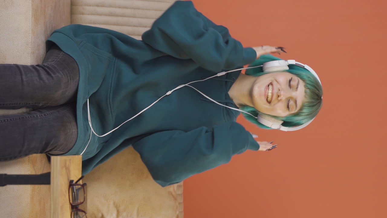 video vertical de una joven feliz escuchando música con auriculares.