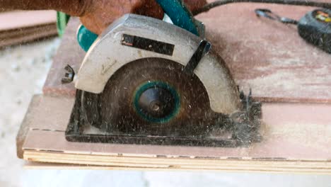 carpenter using circular saw cutting wooden board in carpentry workshop